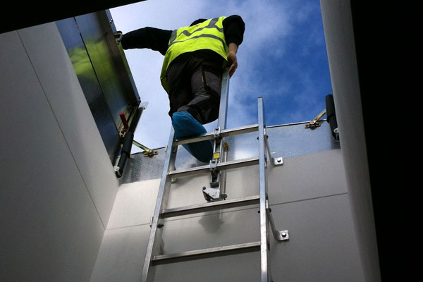 picture of man climbing a fixed vertical ladder through a roof access hatch